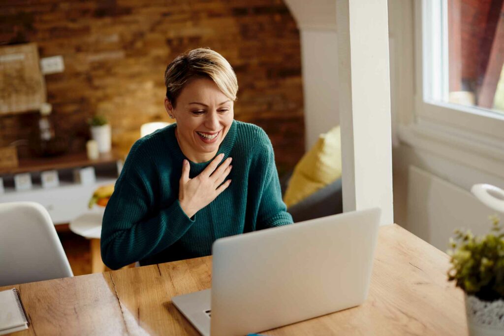 A middle aged woman smiles as she talks with her virtual assistant over Zoom